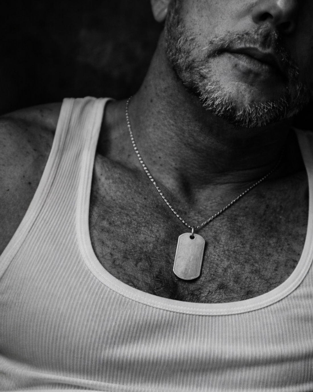 Black and white close-up of man wearing sterling silver dog tag necklace on chest, minimalist and symbolic MARKED jewellery