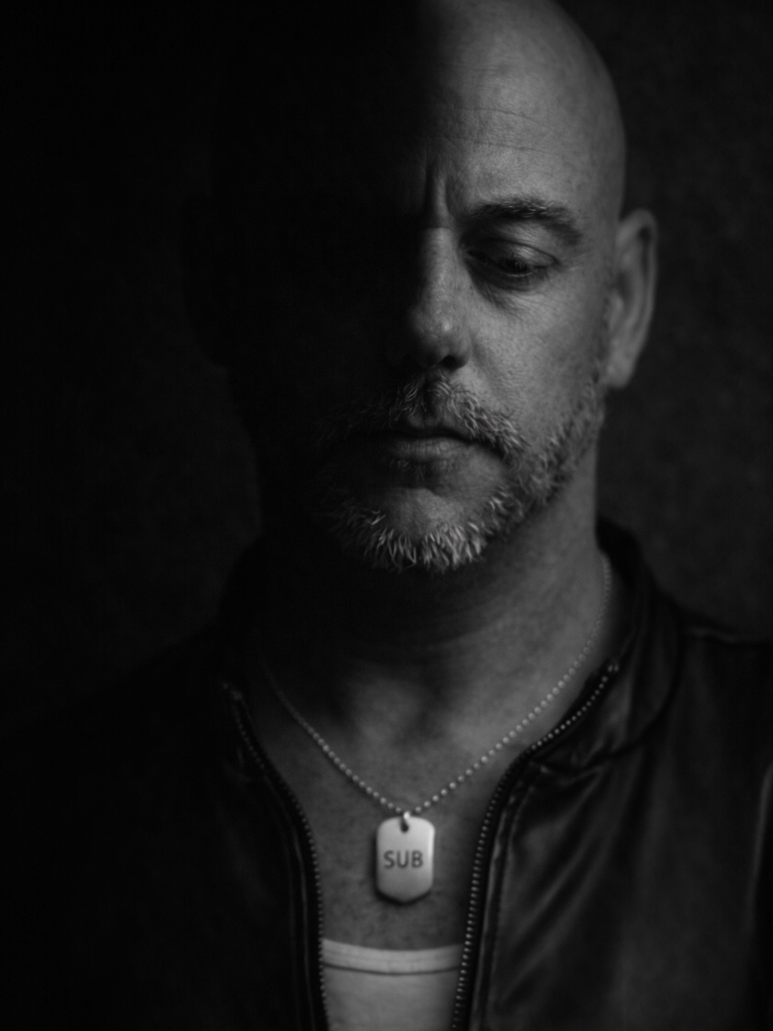 black and white portrait man wearing engraved dog tag necklace reading SUB, minimal mens jewellery, identity jewellery MARKED